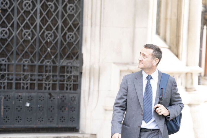 Lee Castleton walking outside next to large gate image